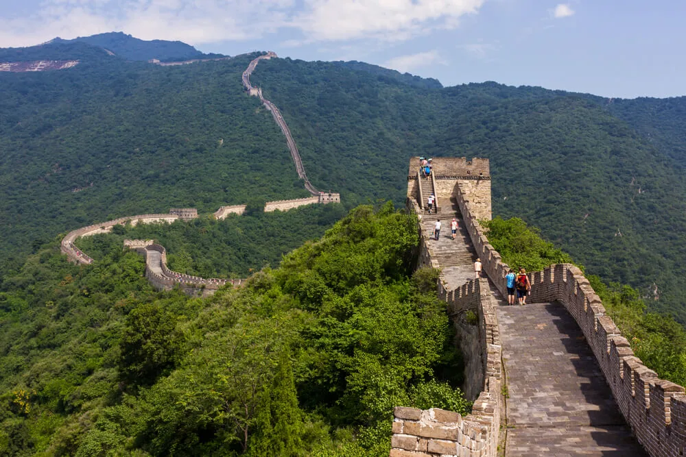 The Great Wall of China climbing green hills past a watchtower
