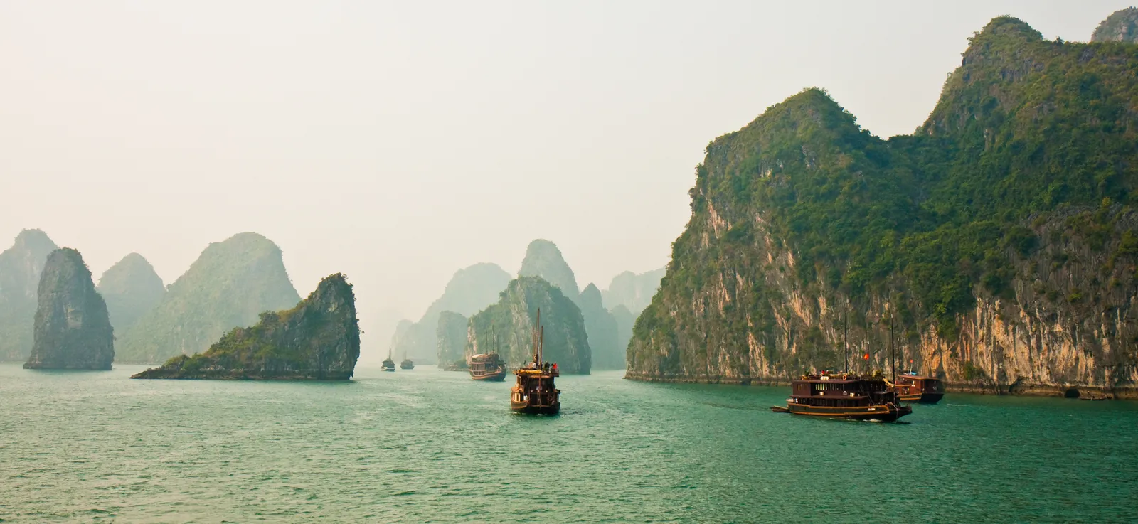 Boats among limestone karsts in Ha Long Bay on a misty morning