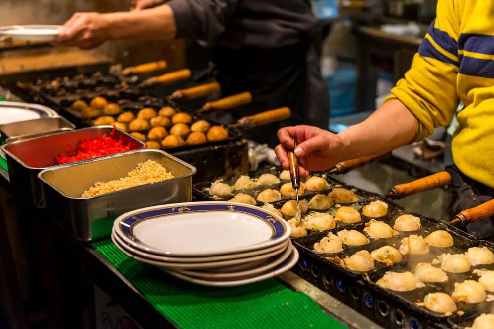 Takoyaki being turned on a hot plate at a street stall in Osaka