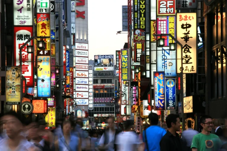 Crowded Shinjuku street in Tokyo lined with illuminated signs